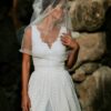 suknia ślubna z koronkowym dekoltem i długim welonem, modelka w otoczeniu kamieni