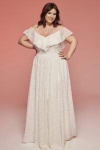 suknia ślubna z odkrytymi ramionami i falbaną, w kolorze białym z delikatnym wzorem.