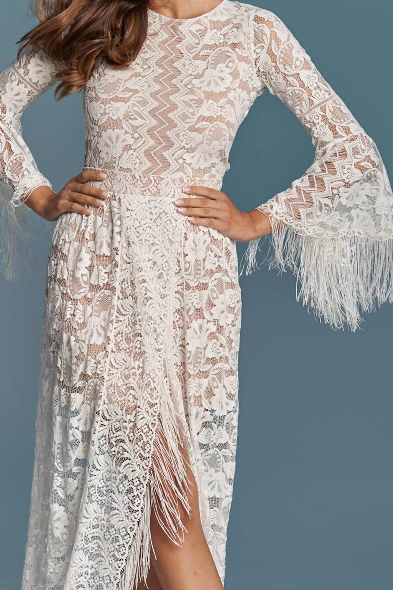 suknia ślubna z koronką, długimi rękawami i frędzlami przy dolnej części.