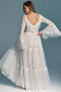 suknia ślubna z długimi rękawami, koronkowym wykończeniem i falbanami u dołu.
