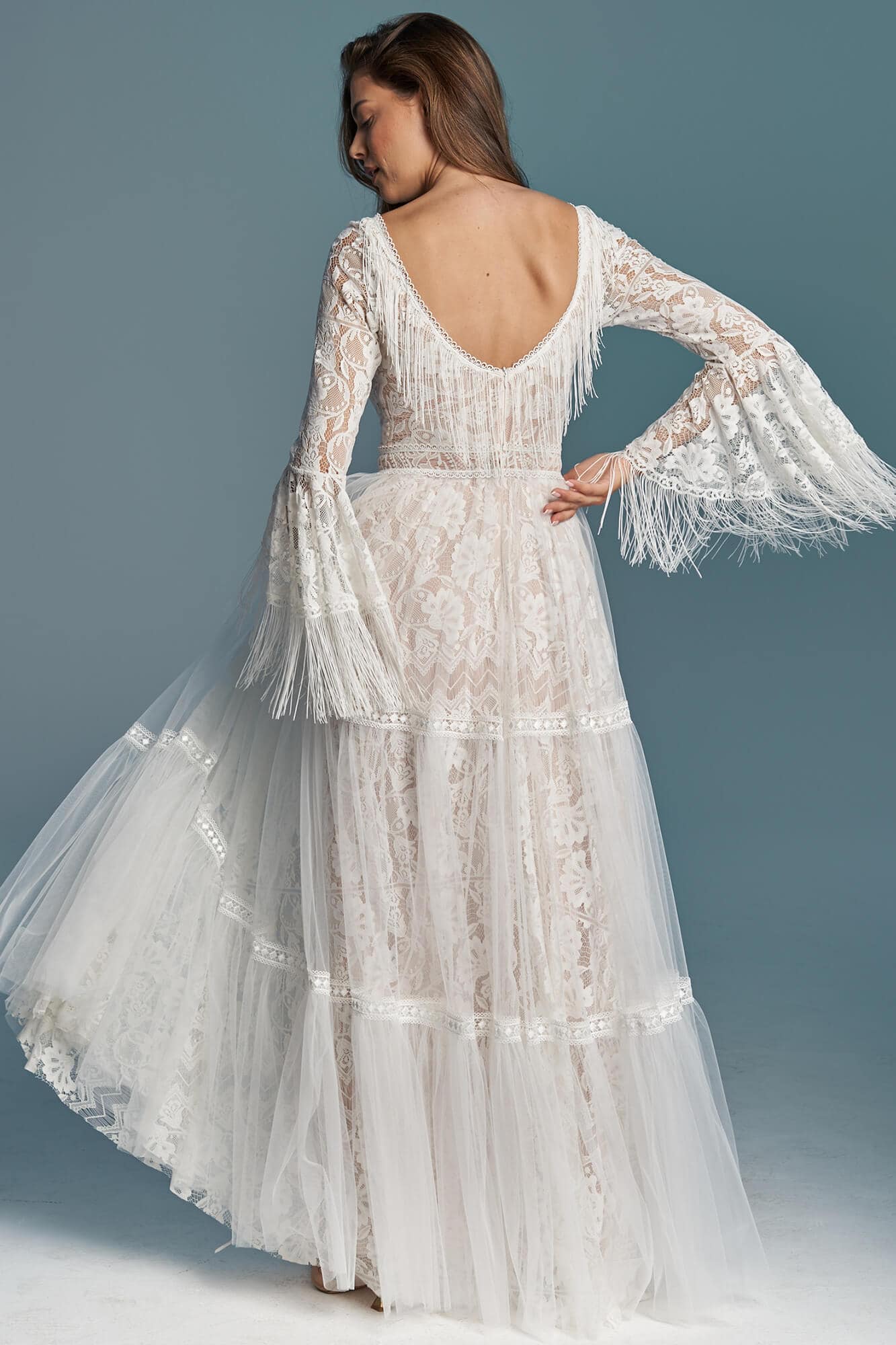 suknia ślubna z długimi rękawami, koronkowym wykończeniem i falbanami u dołu.