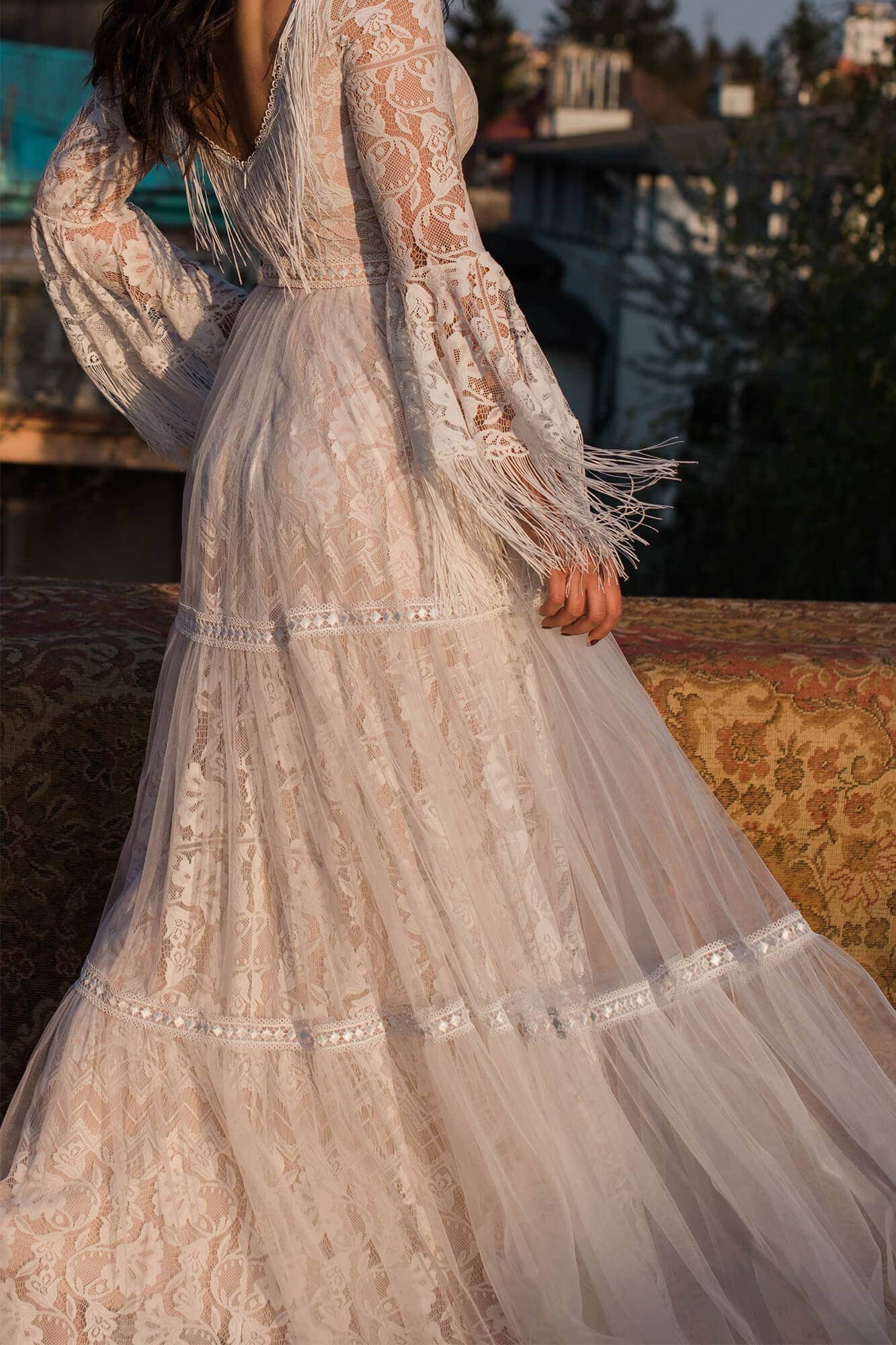 suknia ślubna z długimi rękawami, koronkowym wykończeniem i falbanami na dole.