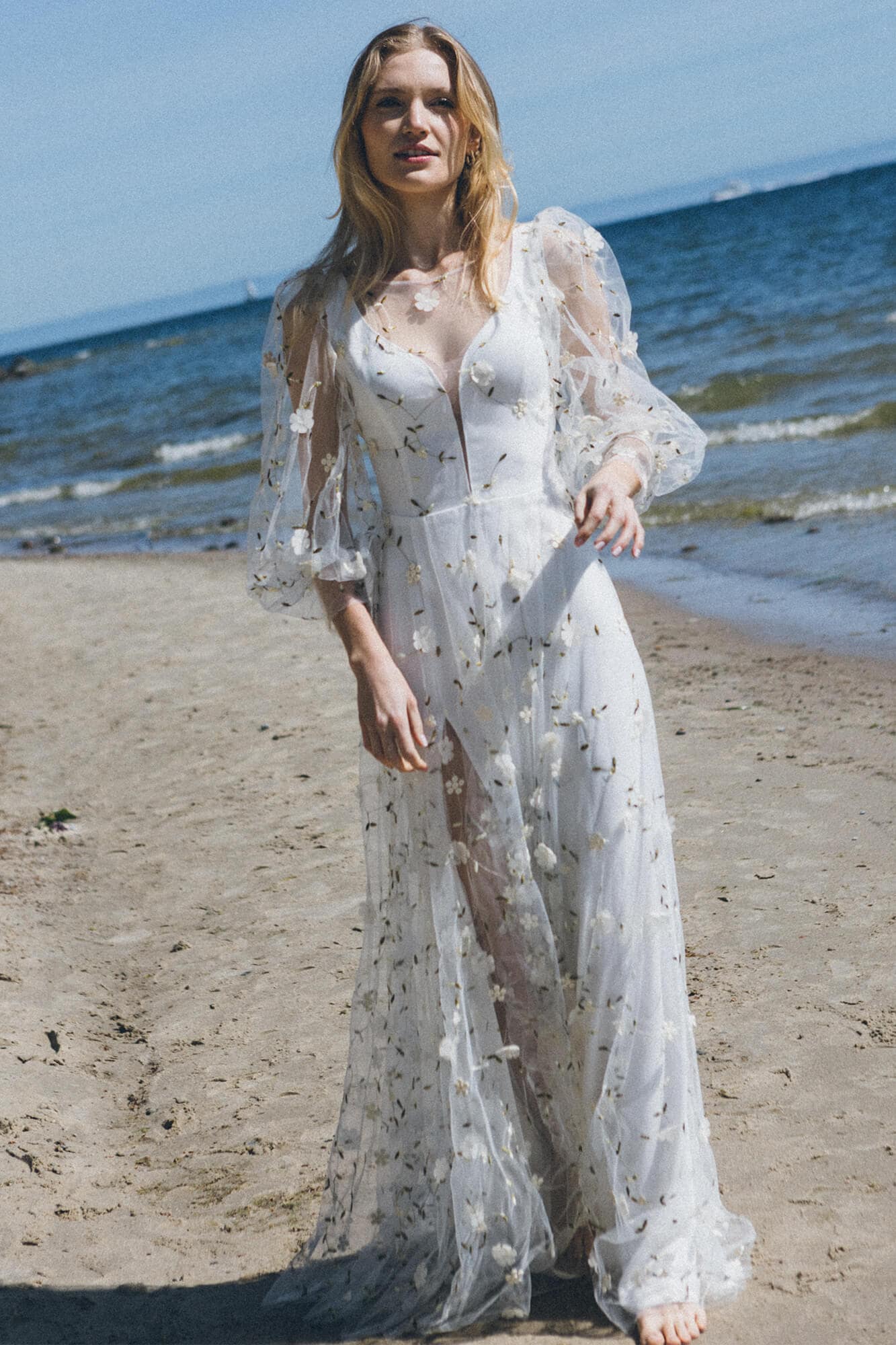 suknia ślubna z koronkowymi rękawami i haftem, widoczna na plaży nad morzem