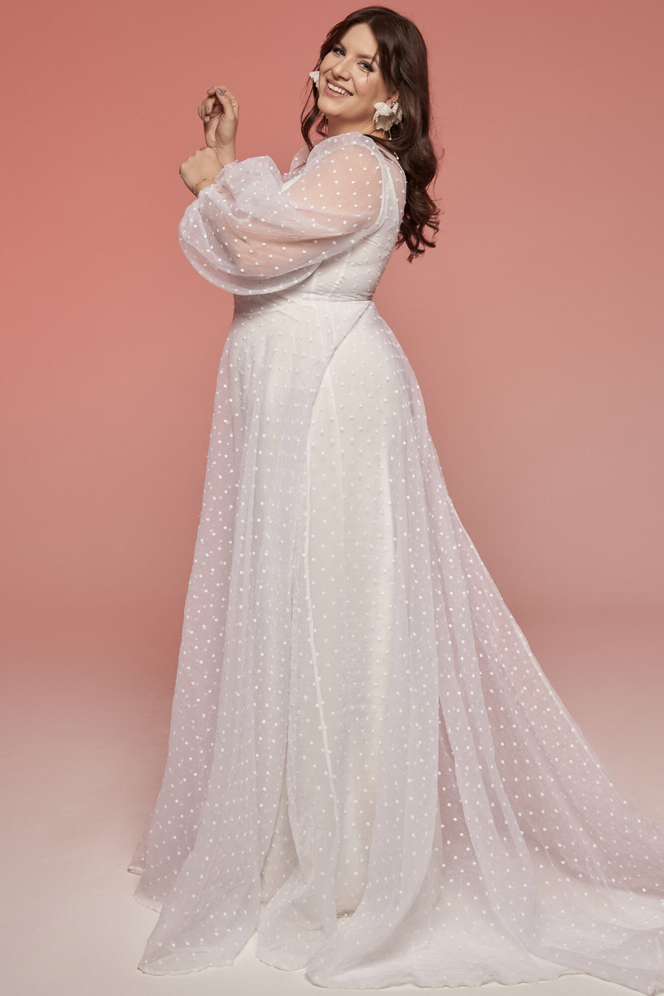 suknia ślubna z długim rękawem i zwiewnym dołem, w kolorze białym z delikatnym wzorem.