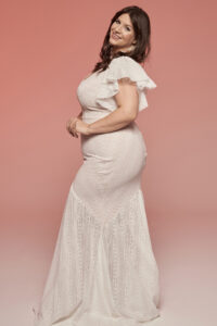 Suknia ślubna z falbanami, z wzorem w delikatne linie i koronkowe detale.