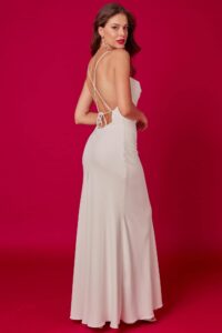 suknia ślubna o prostym kroju, z odkrytymi plecami i długim dołem, na tle różowej ściany