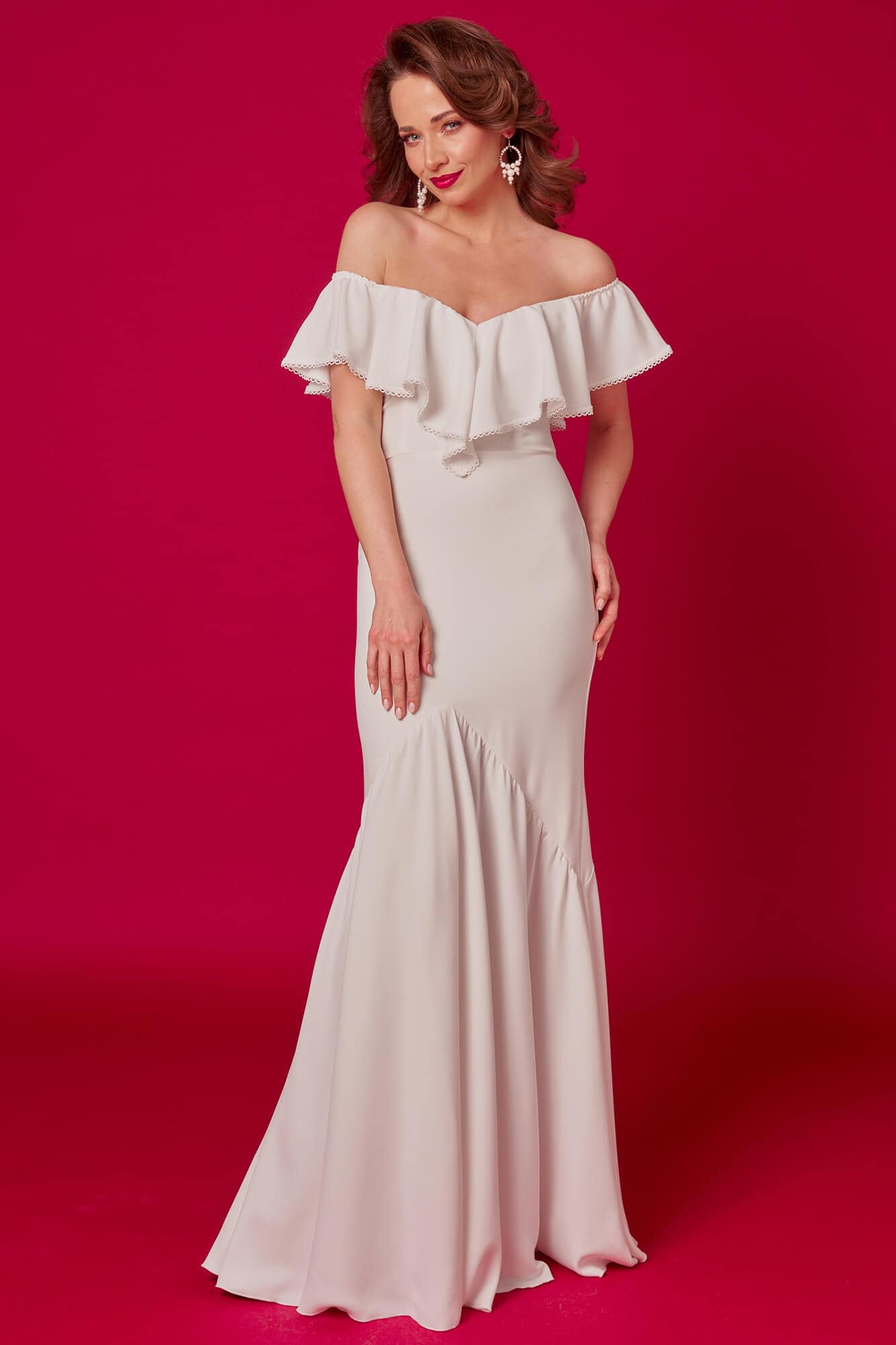 Suknia ślubna z odkrytymi ramionami, z falbaną na górze, w jasnym kolorze.