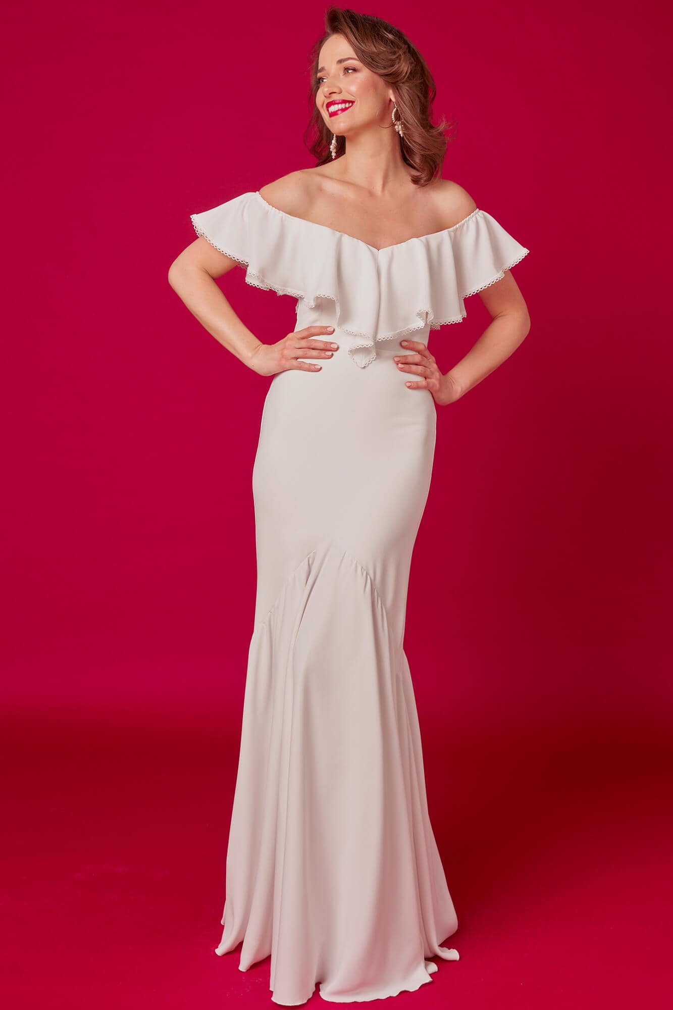 Suknia ślubna z odkrytymi ramionami i falbaną na dekolcie, w kolorze białym.