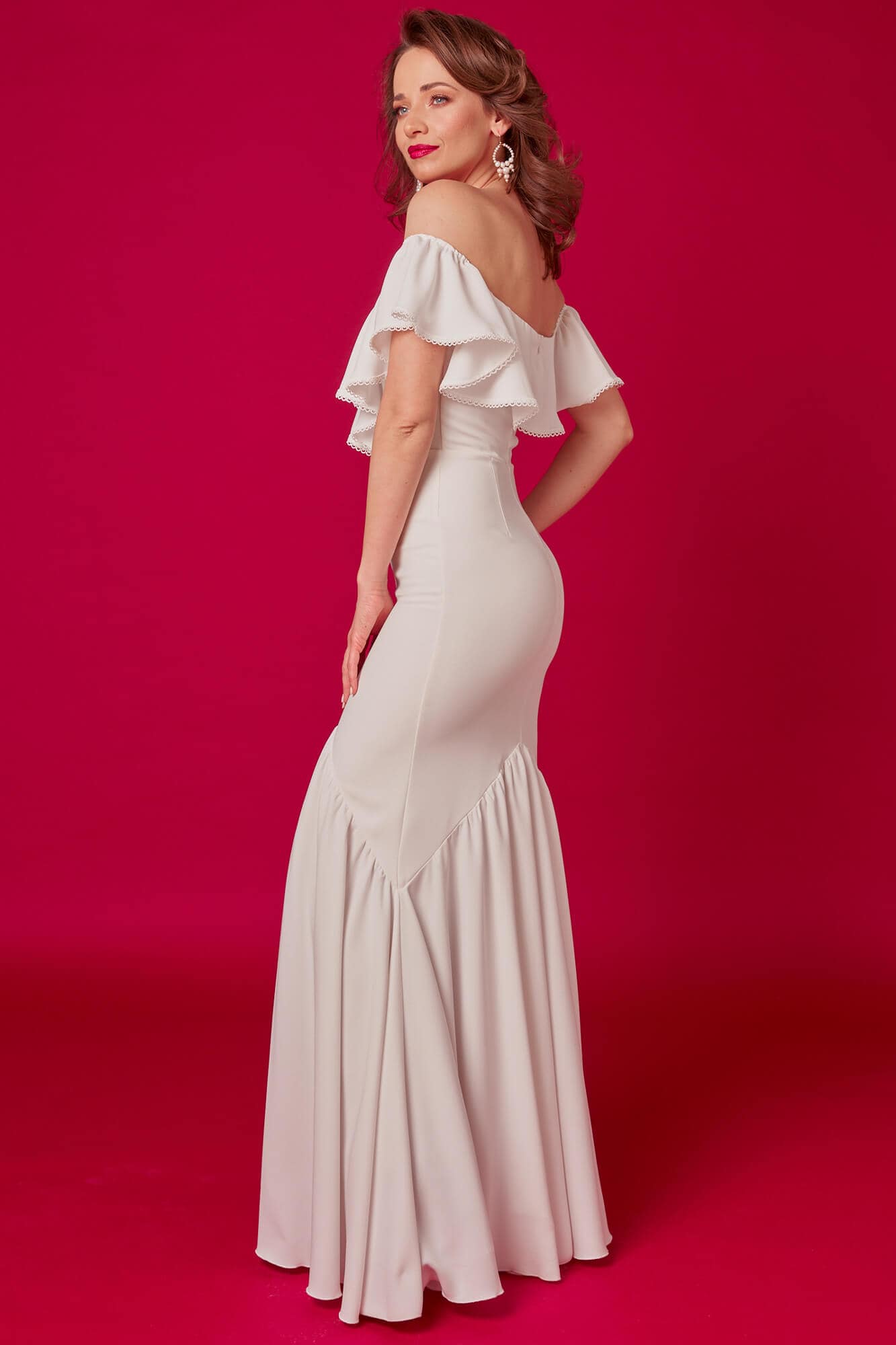 Suknia ślubna z odkrytymi ramionami, dopasowana w górnej części i rozszerzana u dołu.