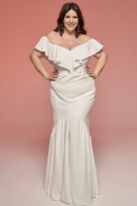 suknia ślubna z odkrytymi ramionami, dopasowana w talii, z falbanami na dekolcie