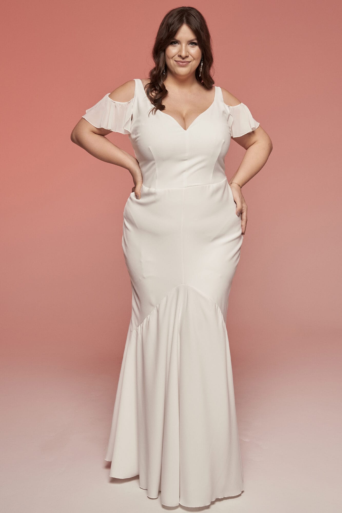 Suknia ślubna w kolorze białym z odkrytymi ramionami i dopasowanym fasonem.