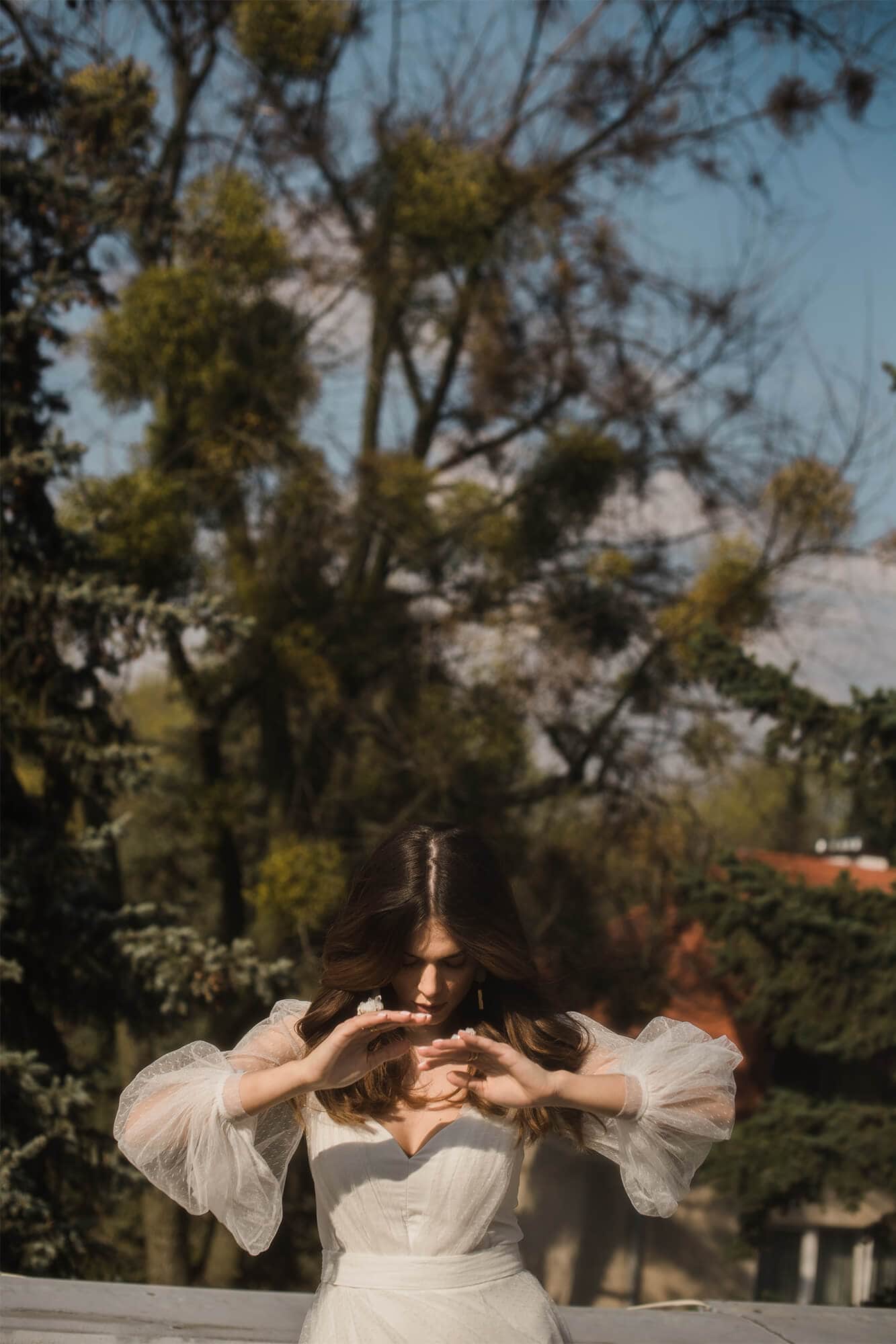 suknia ślubna z długimi rękawami, widoczna w plenerze z drzewami w tle