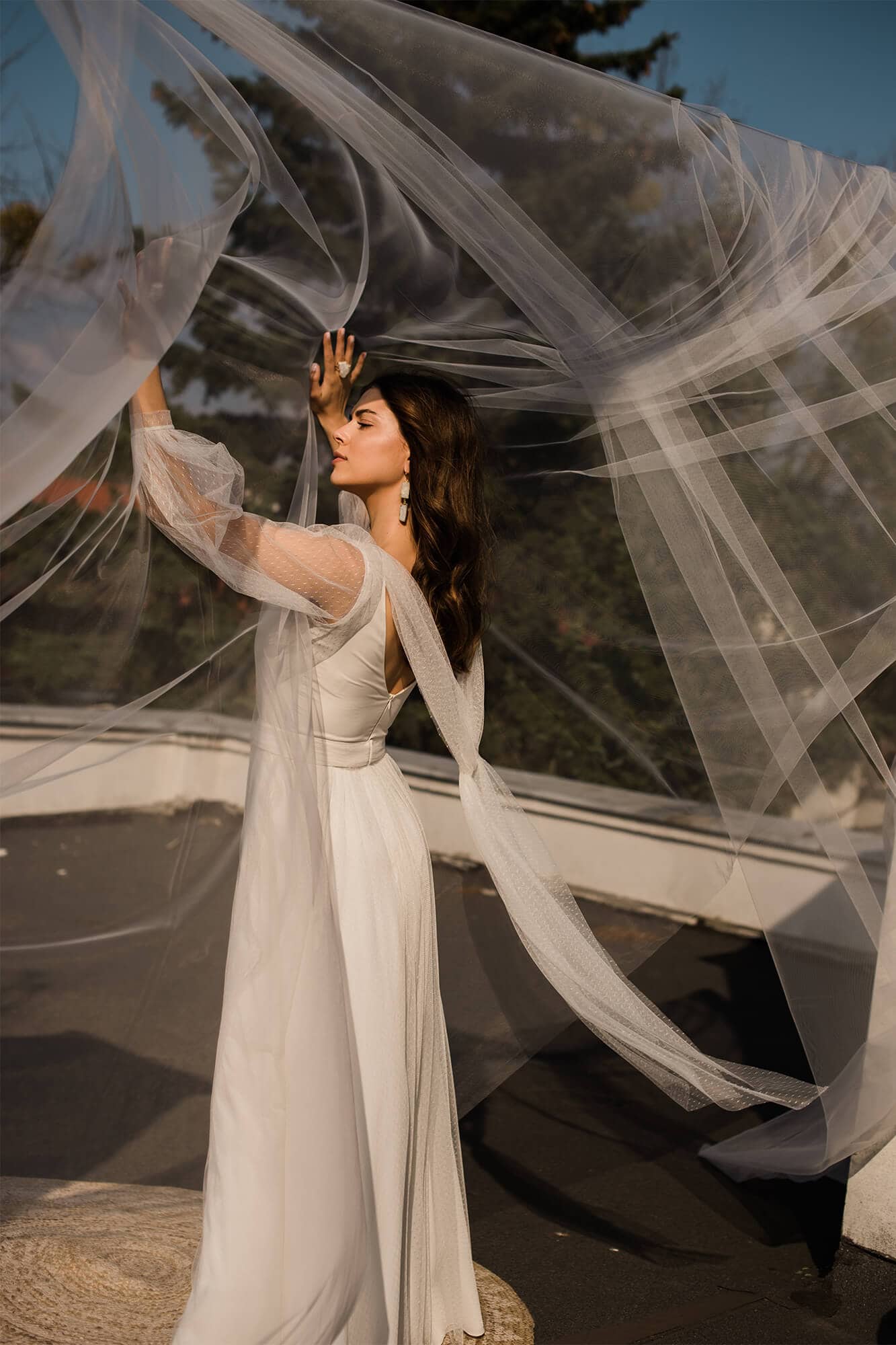 suknia ślubna z długimi rękawami, z tiulowym welonem w tle