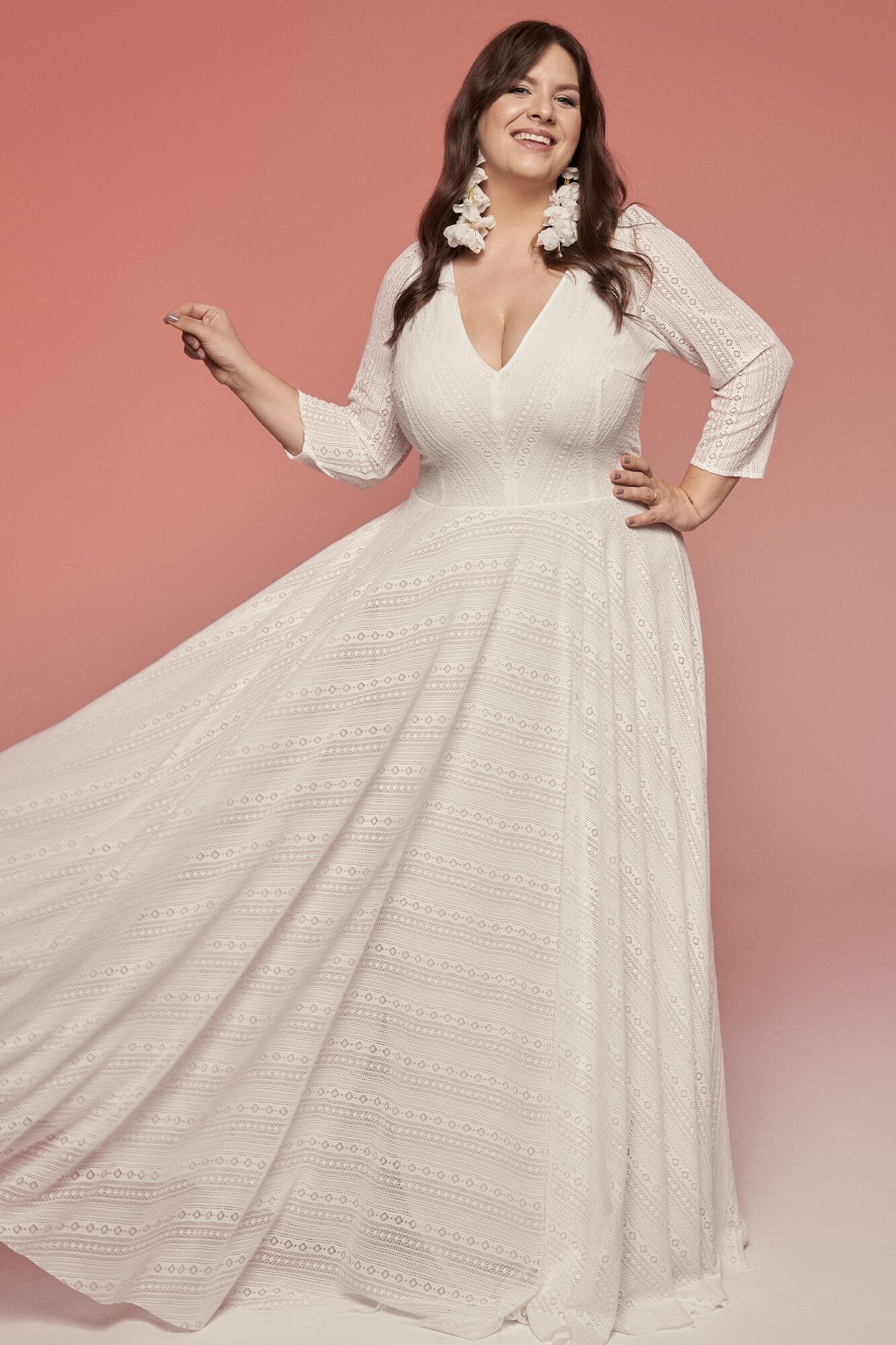 suknia ślubna o długich rękawach i dekolcie w serek, wykonana z lekkiego materiału.