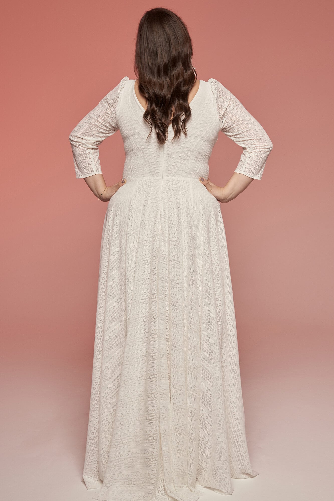 suknia ślubna z długim rękawem i rozkloszowanym dołem, widok z tyłu na tle różowego tła