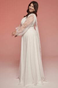 Suknia ślubna z długimi rękawami i delikatnym materiałem, w kolorze białym.