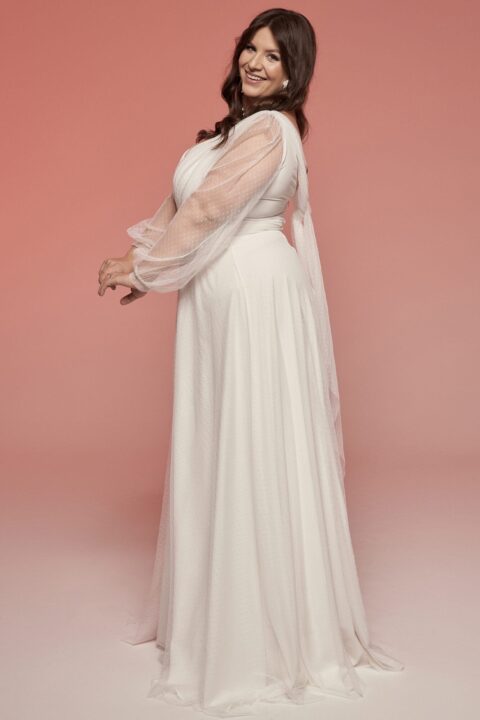 Suknia ślubna z długimi rękawami i delikatnym materiałem, w kolorze białym.