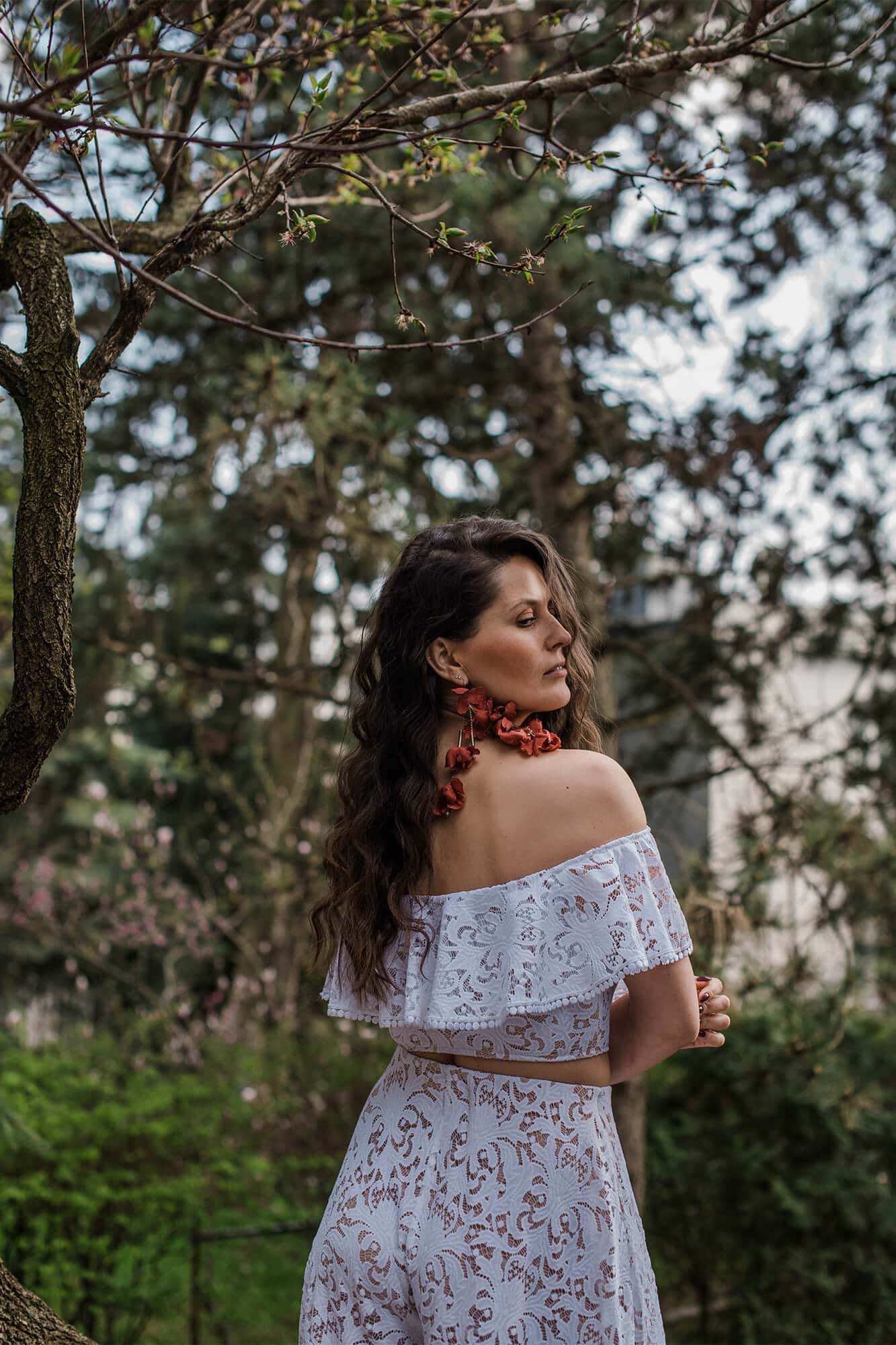 suknia w kolorze białym z odkrytymi ramionami, z koronkowym wzorem i falbaną na górze