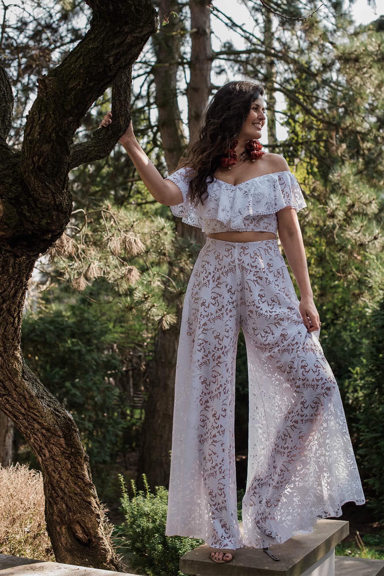 suknia z szerokimi nogawkami i falbaniastym dekoltem, w kwiatowy wzór, na tle drzew