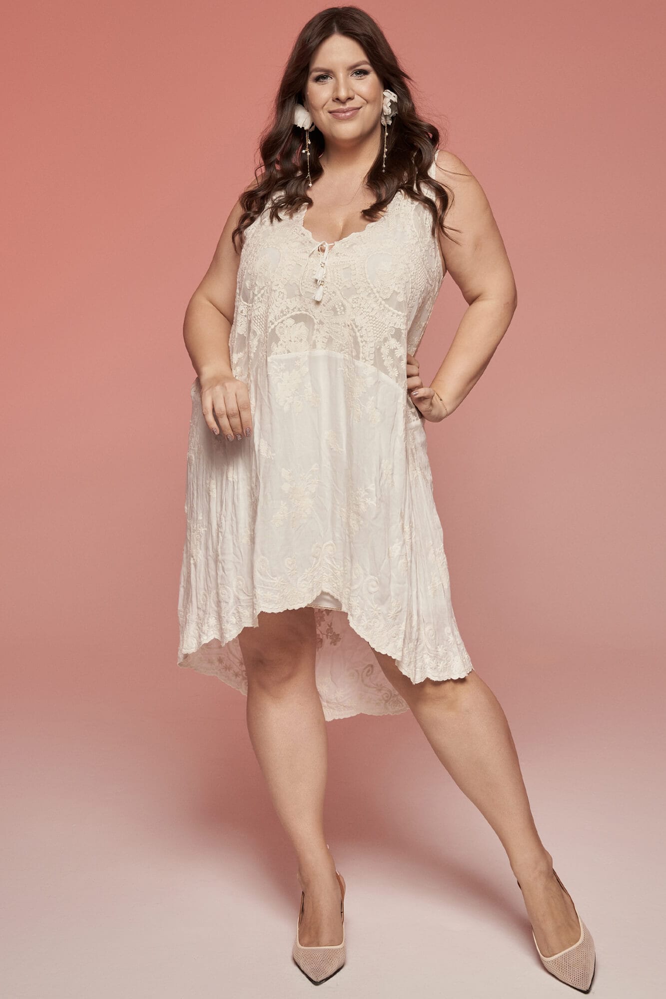 suknia w kolorze jasnym z koronkowymi detalami, z dekoltem w kształcie litery V i asymetrycznym dołem