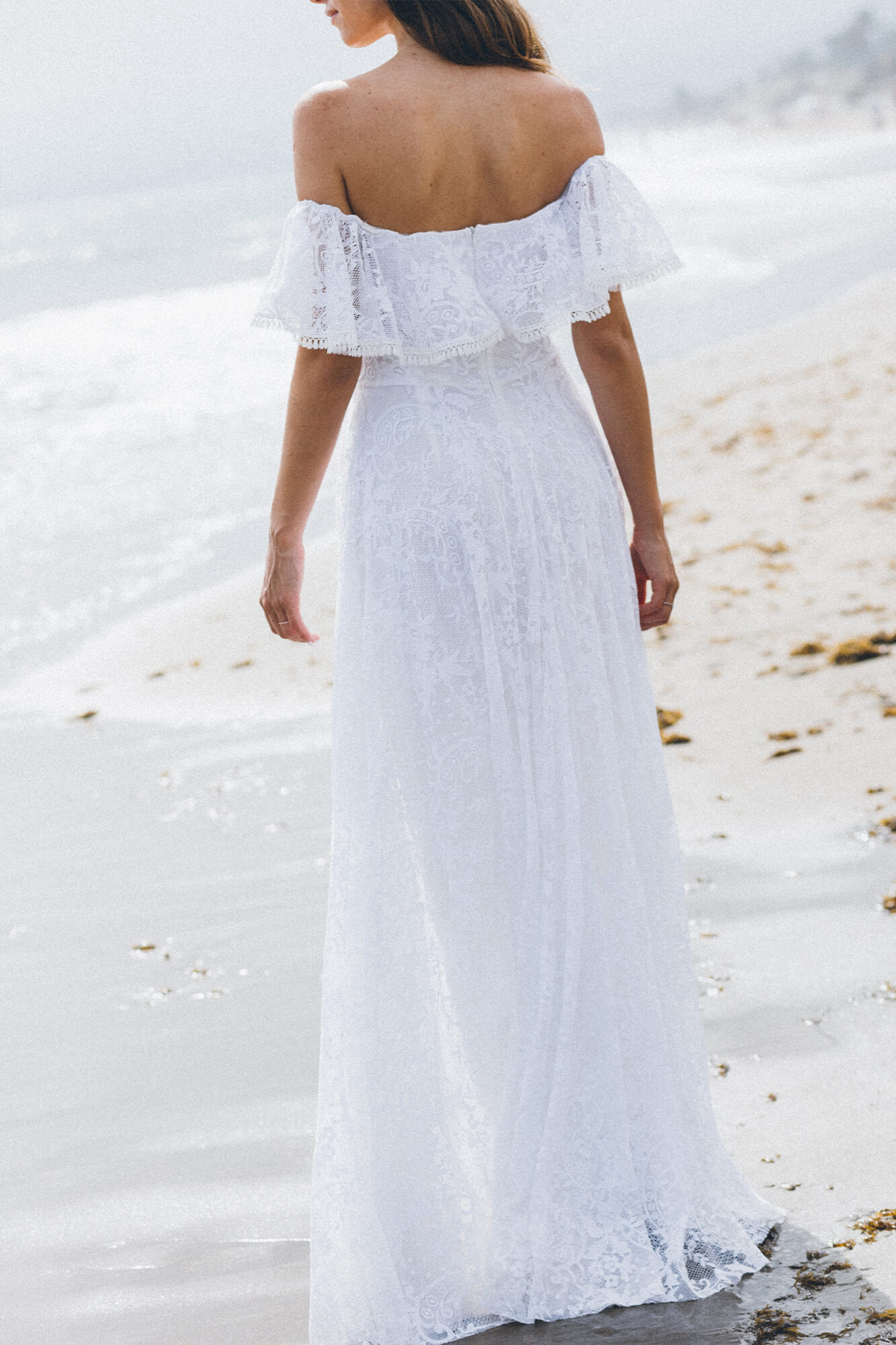 suknia ślubna z długim dołem i bufiastymi rękawami, widoczna z tyłu na plaży