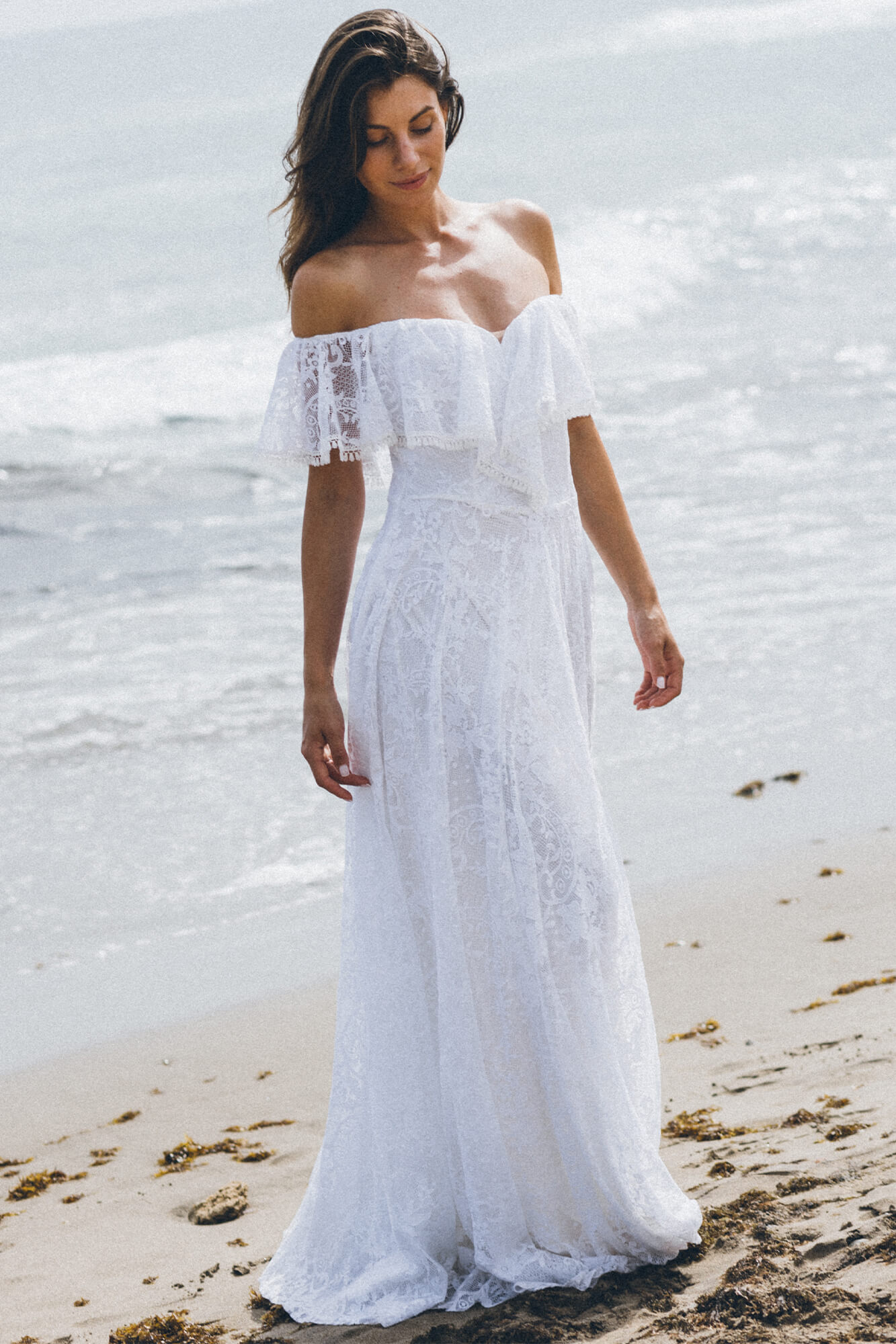 suknia ślubna z koronkowymi rękawami, biała, z długim dołem, na tle plaży i morza