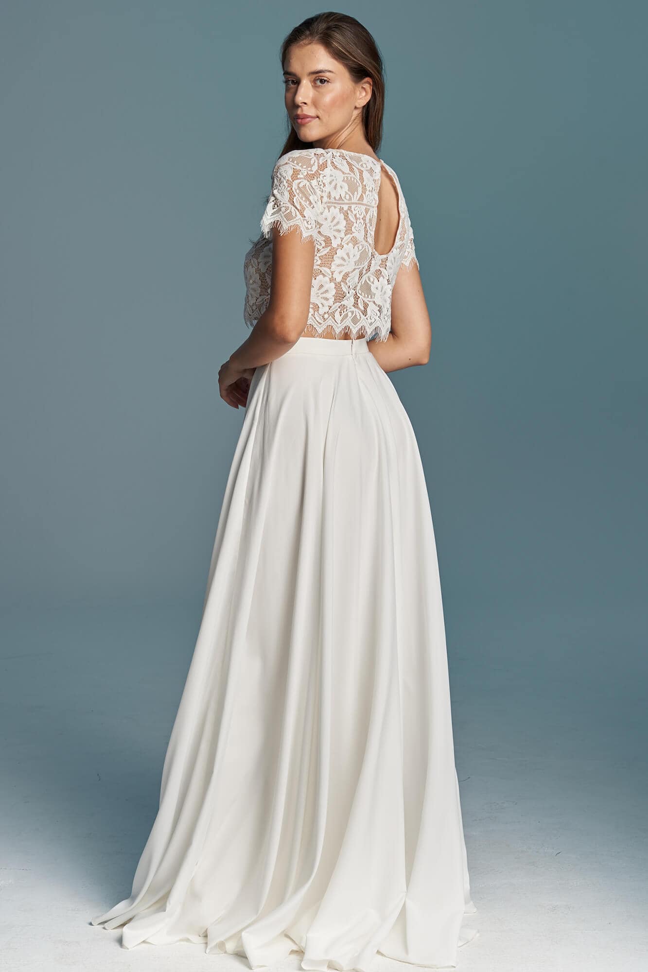suknia ślubna z koronkowym górnym elementem i długą, gładką spódnicą w kolorze białym.