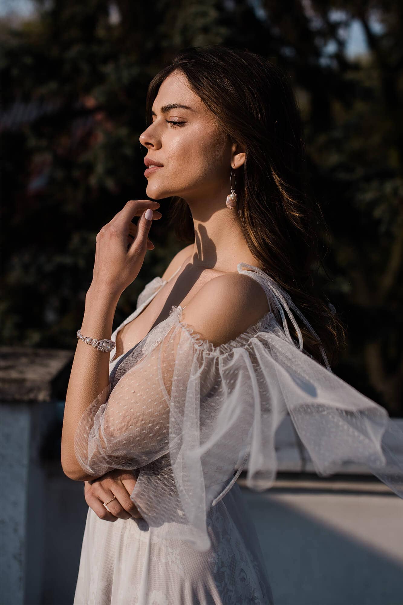 Suknia ślubna o delikatnych, przezroczystych rękawach, z kwiatu i koronkowymi detalami.