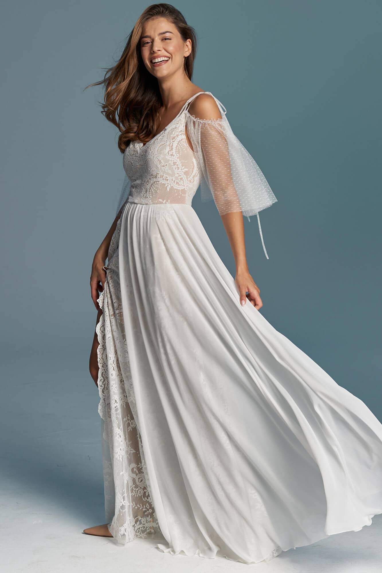 Suknia ślubna z koronkowym gorsetem i zwiewnym, długim dołem w kolorze białym.