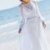 suknia ślubna z długimi koronkowymi rękawami, z lekkiego materiału, na tle plaży i morza