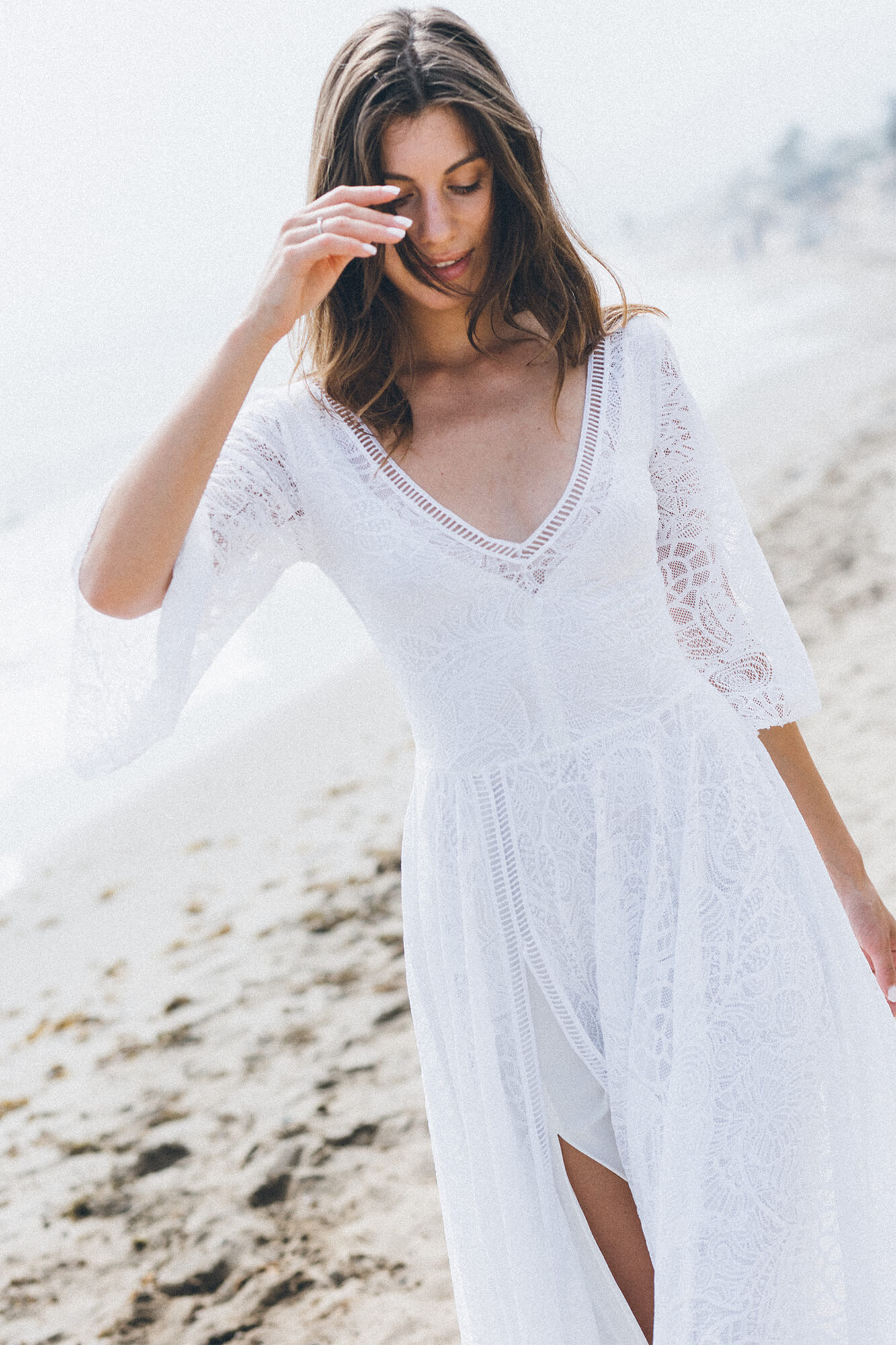 suknia ślubna z koronkowymi rękawami i dekoltem w serek, na tle plaży