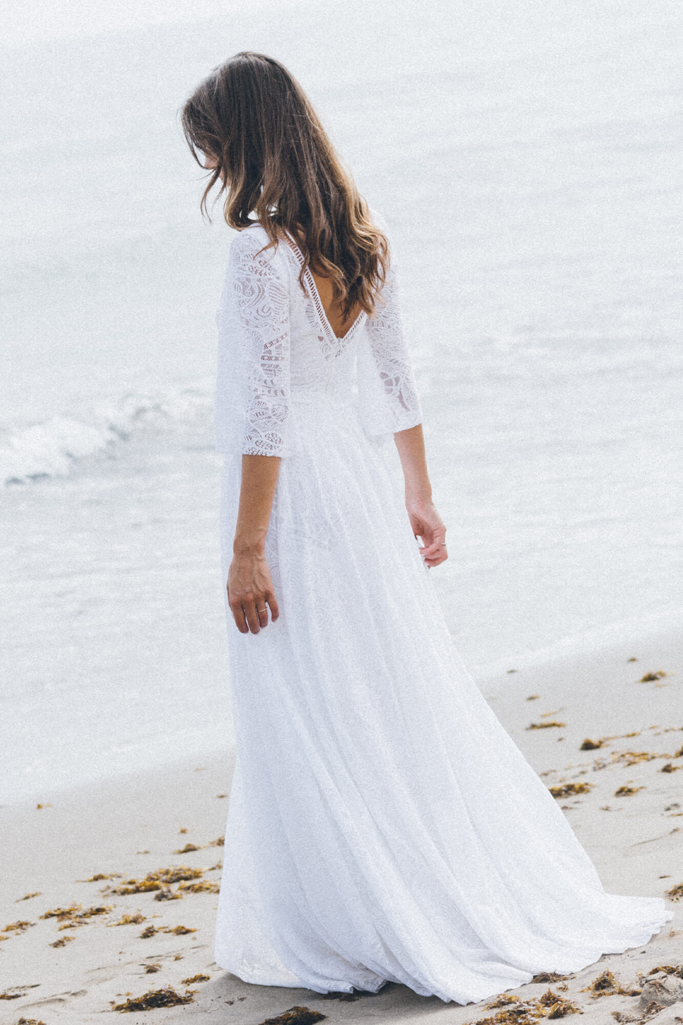 suknia ślubna z długimi rękawami, widoczna z tyłu, na plaży przy wodzie