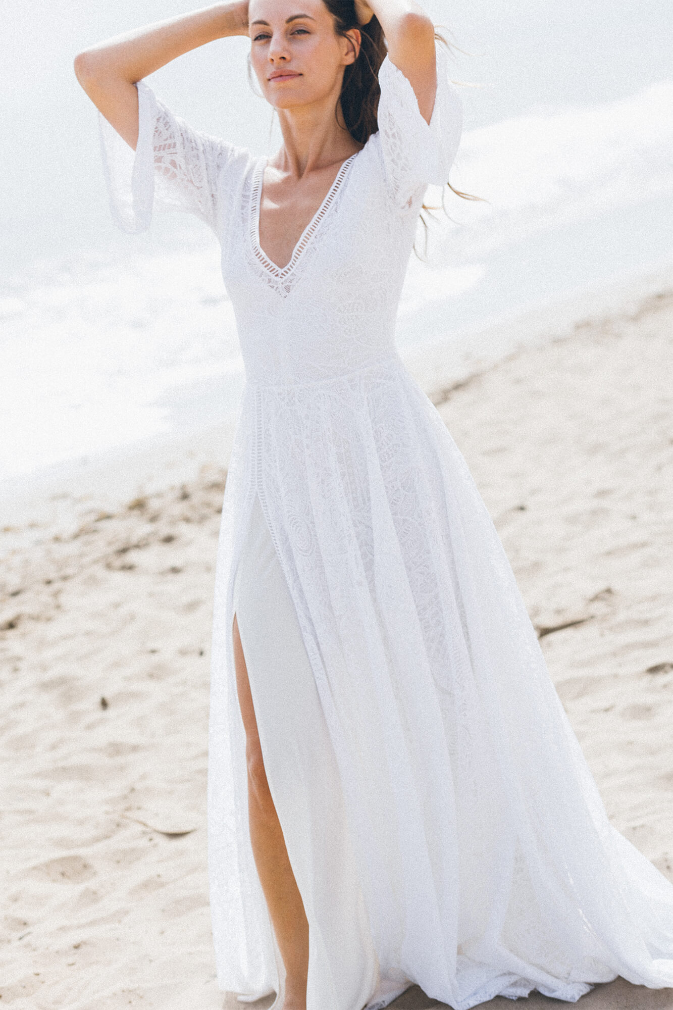 suknia ślubna z długim rękawem, dekoltem w serek i rozcięciem na nogawce, na plaży