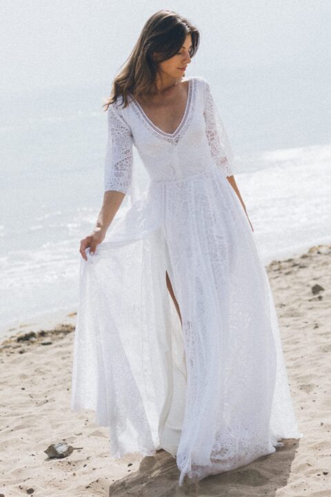 suknia ślubna z długimi rękawami i rozcięciem, na tle plaży i morza