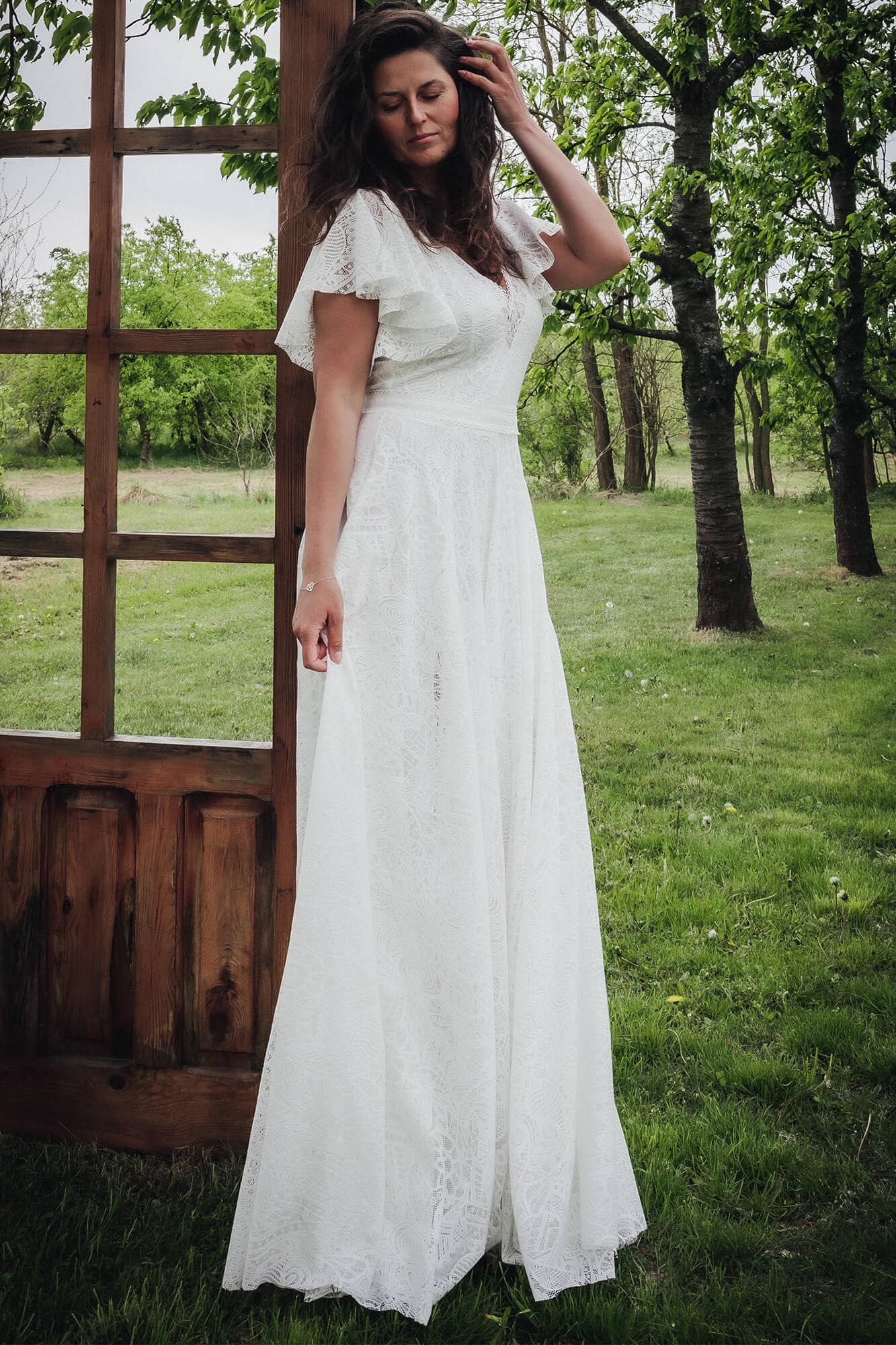 Suknia ślubna z krótkimi, falbaniastymi rękawami, wykonana z białego materiału w delikatny wzór.