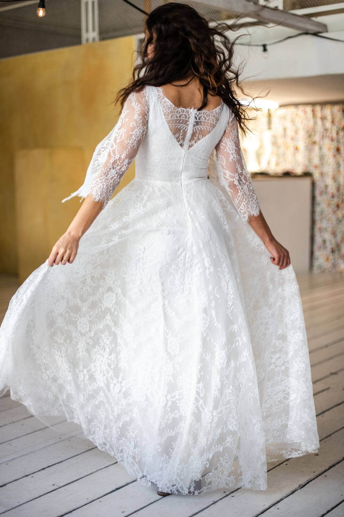 suknia ślubna z koronkowymi rękawami i długim, zwiewnym dołem w kolorze białym.