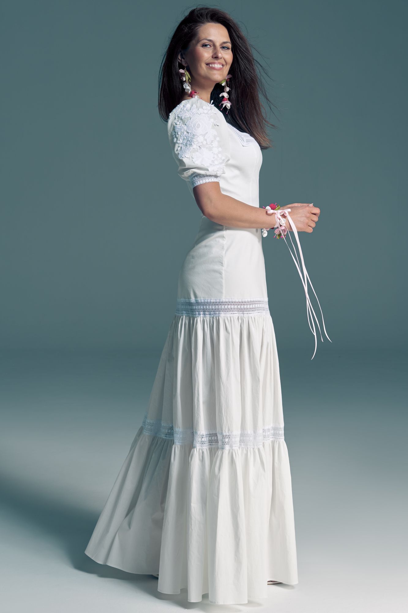 suknia ślubna z długim, białym dołem i krótkim rękawem, z ozdobnymi sznurkami przy nadgarstkach