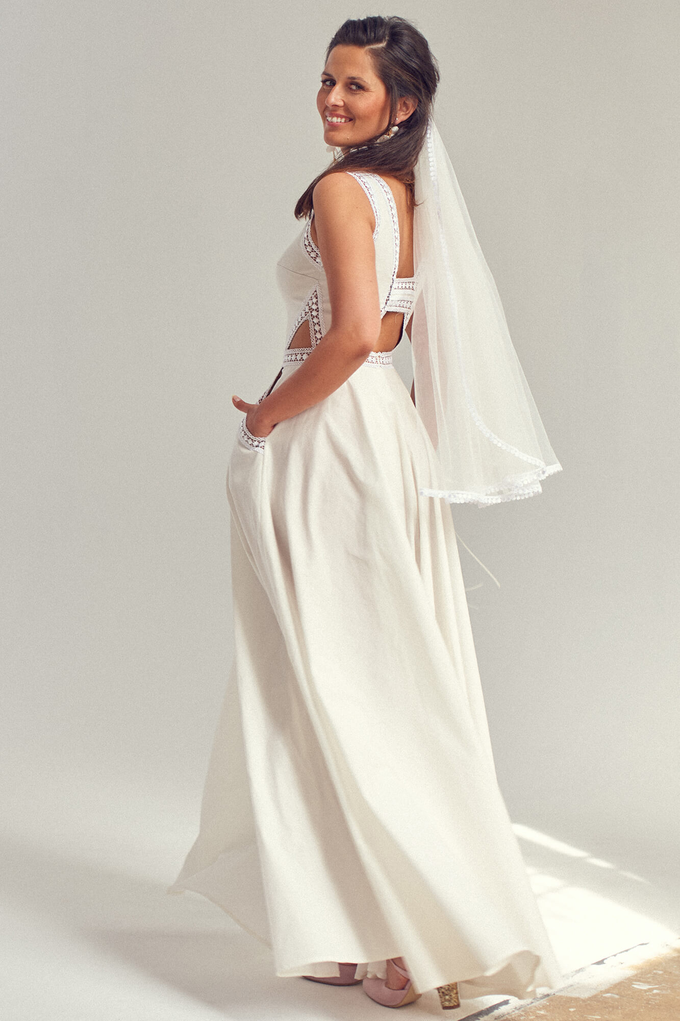 suknia ślubna z koronkowym topem i długim, gładkim dołem, z welonem na głowie kobiety