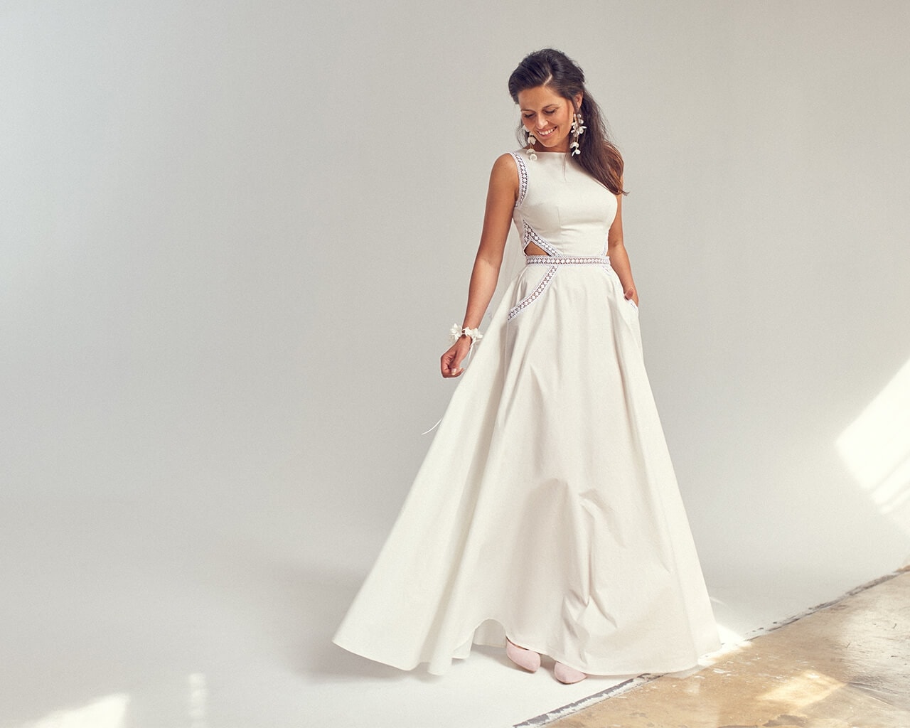 suknia ślubna z długim dołem, bez rękawów, z ozdobnymi wycięciami i kieszeniami, w kolorze białym