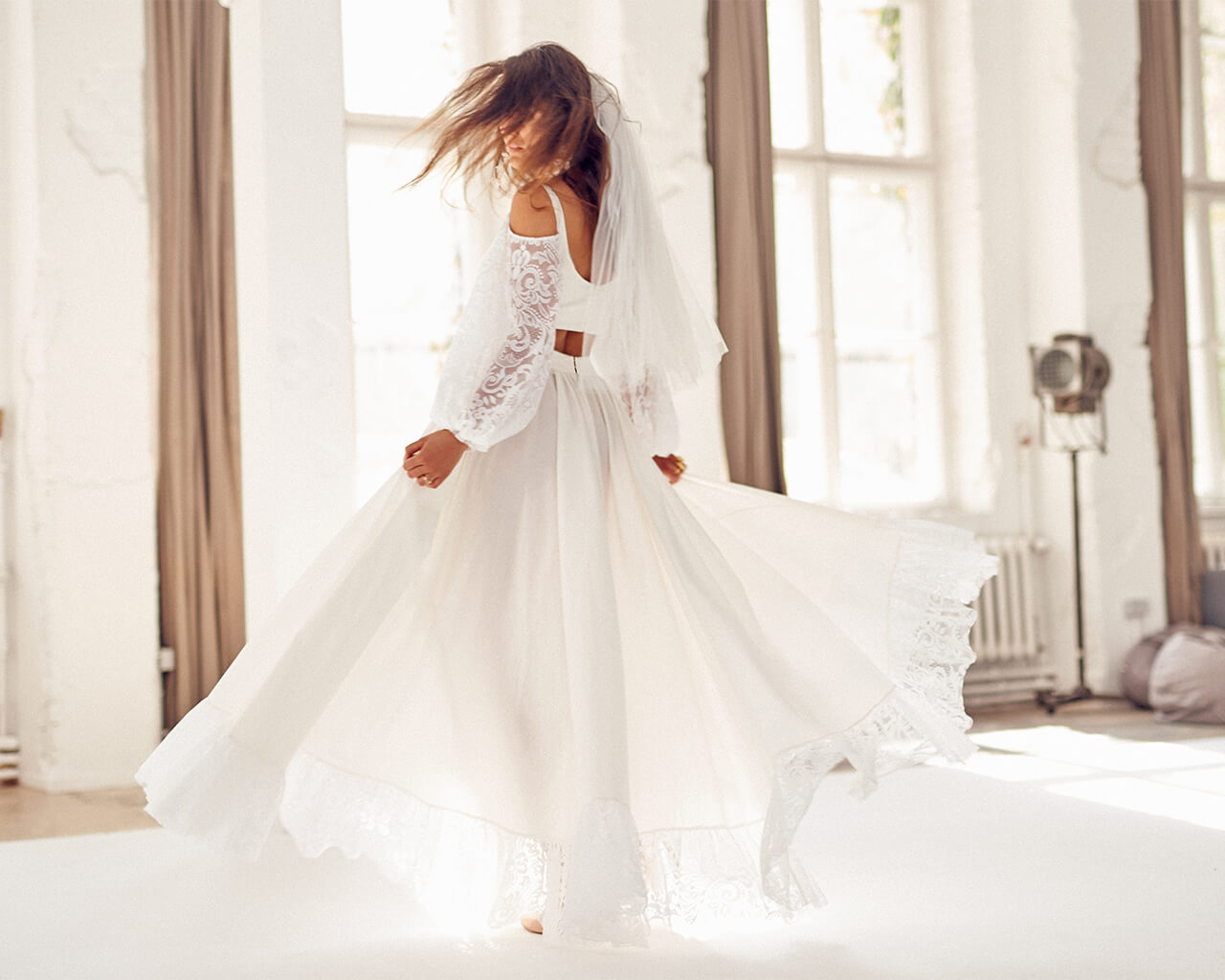 suknia ślubna z długimi koronkowymi rękawami i welonem, kręcąca się w jasnym pomieszczeniu