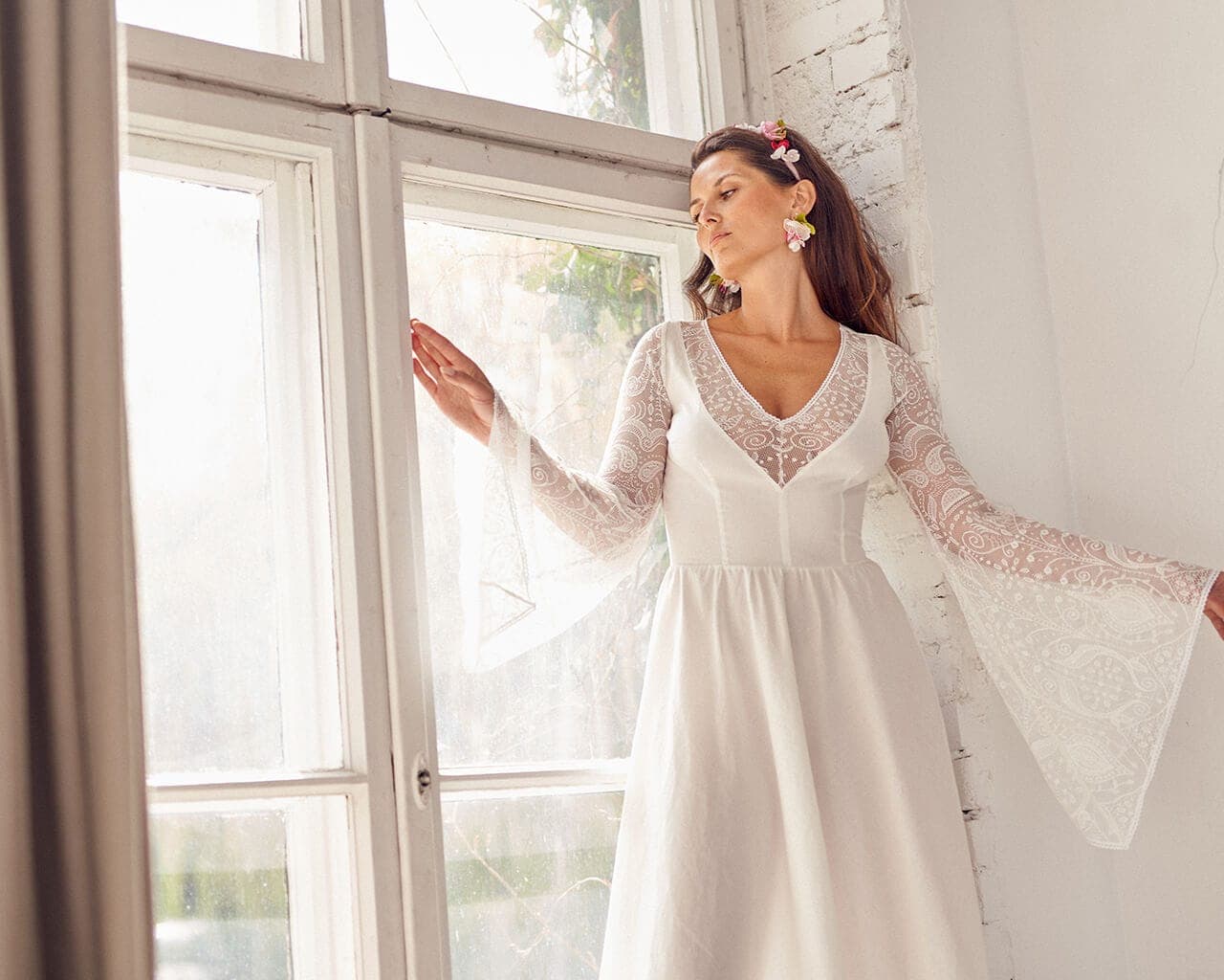 Suknia ślubna z długimi rękawami, wykonana z lekkiego materiału, z dekoltem w serek.