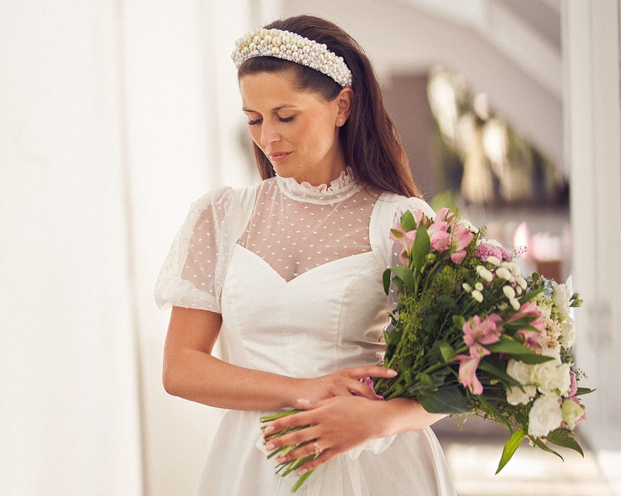 suknia ślubna z krótkim rękawem, przezroczystą górą i bukietem kwiatów w dłoniach kobiety