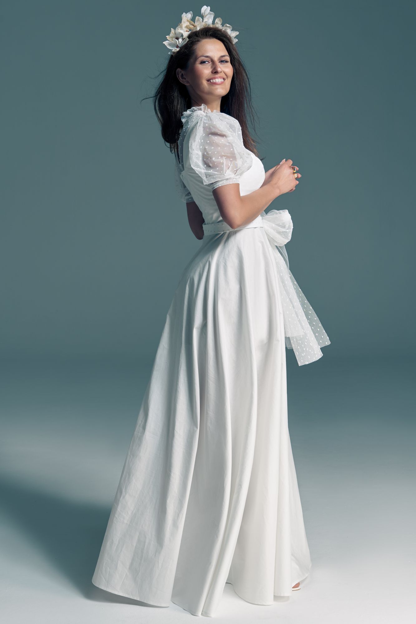 suknia ślubna z krótkimi, przezroczystymi rękawami i wstążką w talii, modelka z kwiatami we włosach