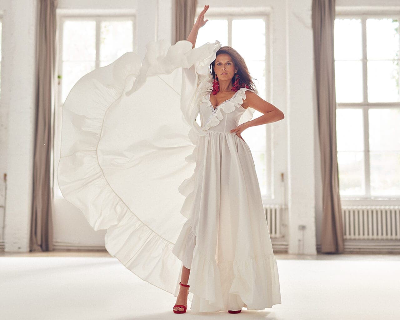 Suknia ślubna z dekoltem w kształcie litery V, z falbanami i długim rękawem.