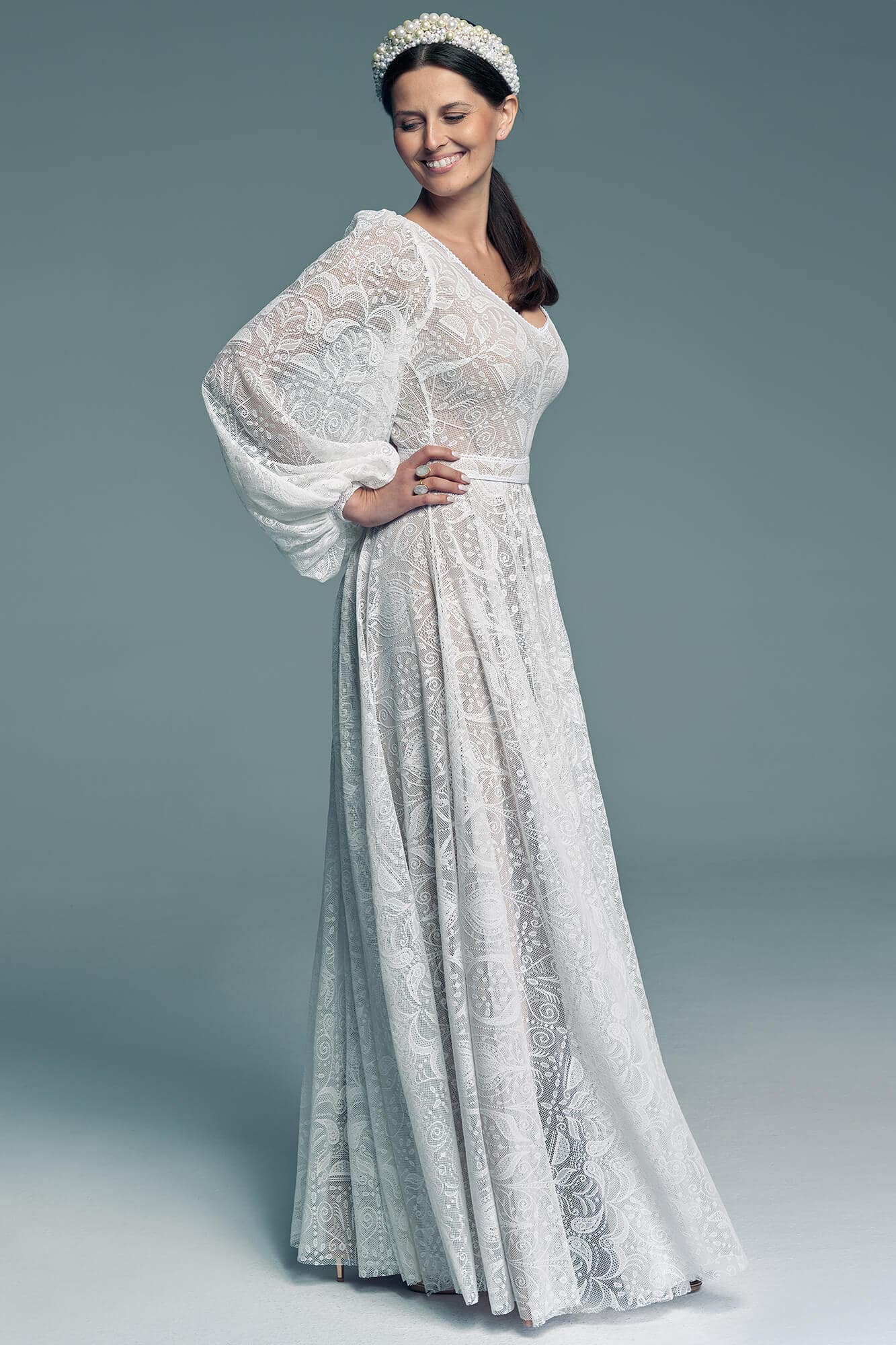 suknia ślubna z długimi rękawami, wykonana z białego materiału z koronkowymi detalami