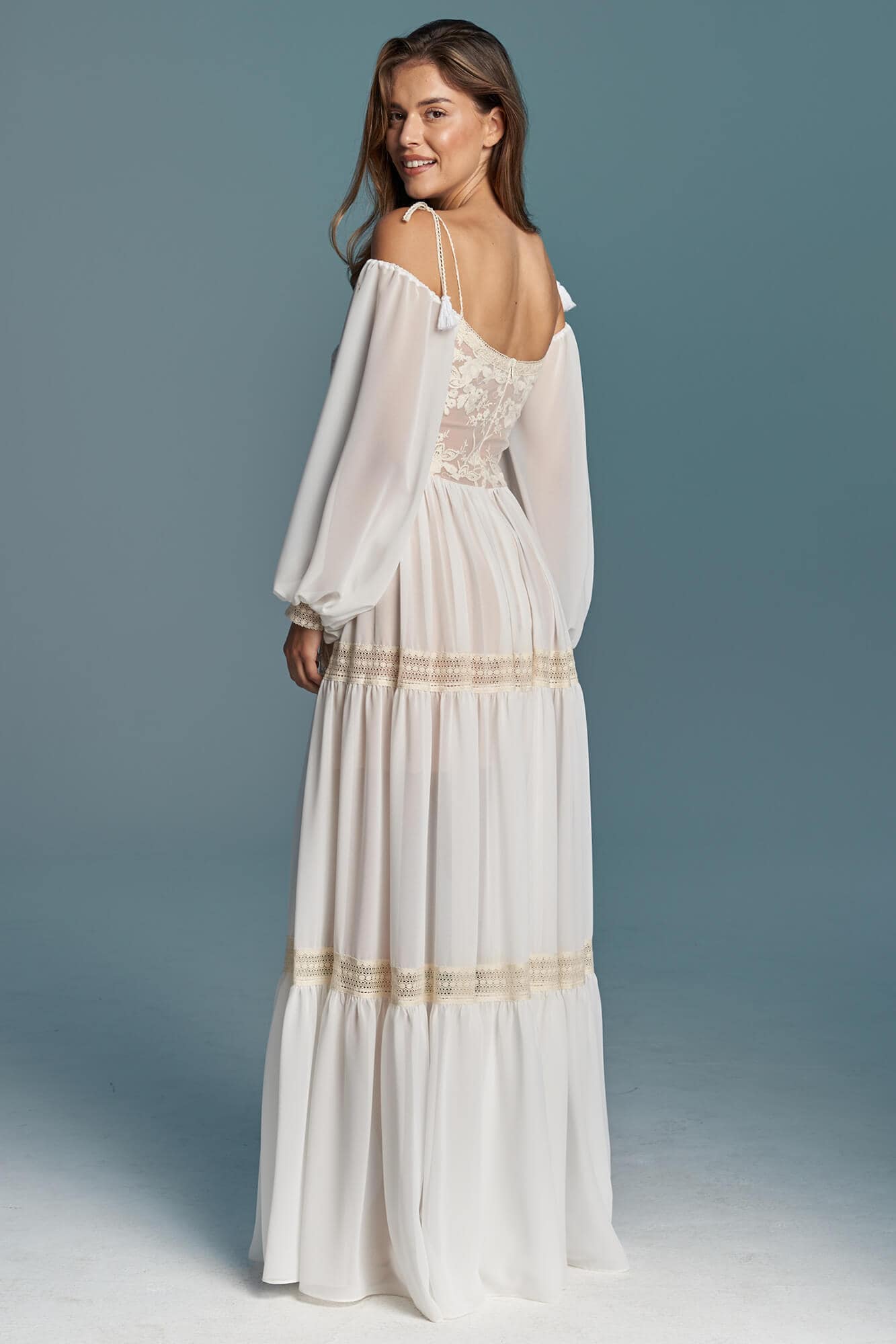 suknia ślubna z długimi rękawami i odkrytymi plecami, w kolorze białym z ozdobnym wykończeniem