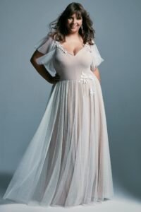 suknia ślubna z delikatnymi rękawami i ozdobnym detalem na biodrze, w jasnym kolorze.