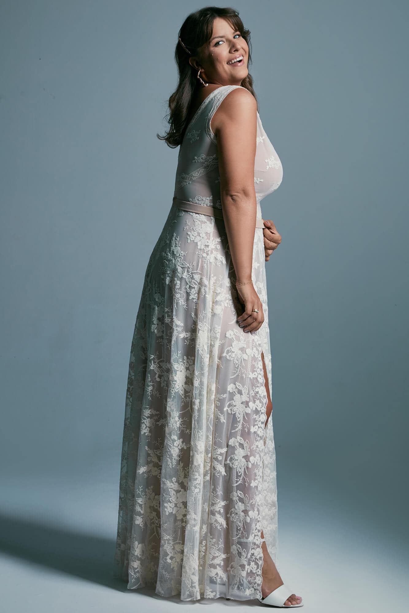 Suknia ślubna o długim kroju z koronkowym detalem, widoczna z boku.