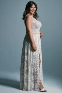 suknia ślubna z koronkowym wzorem, odsłaniająca nogę, na modelce w pozycji bocznej