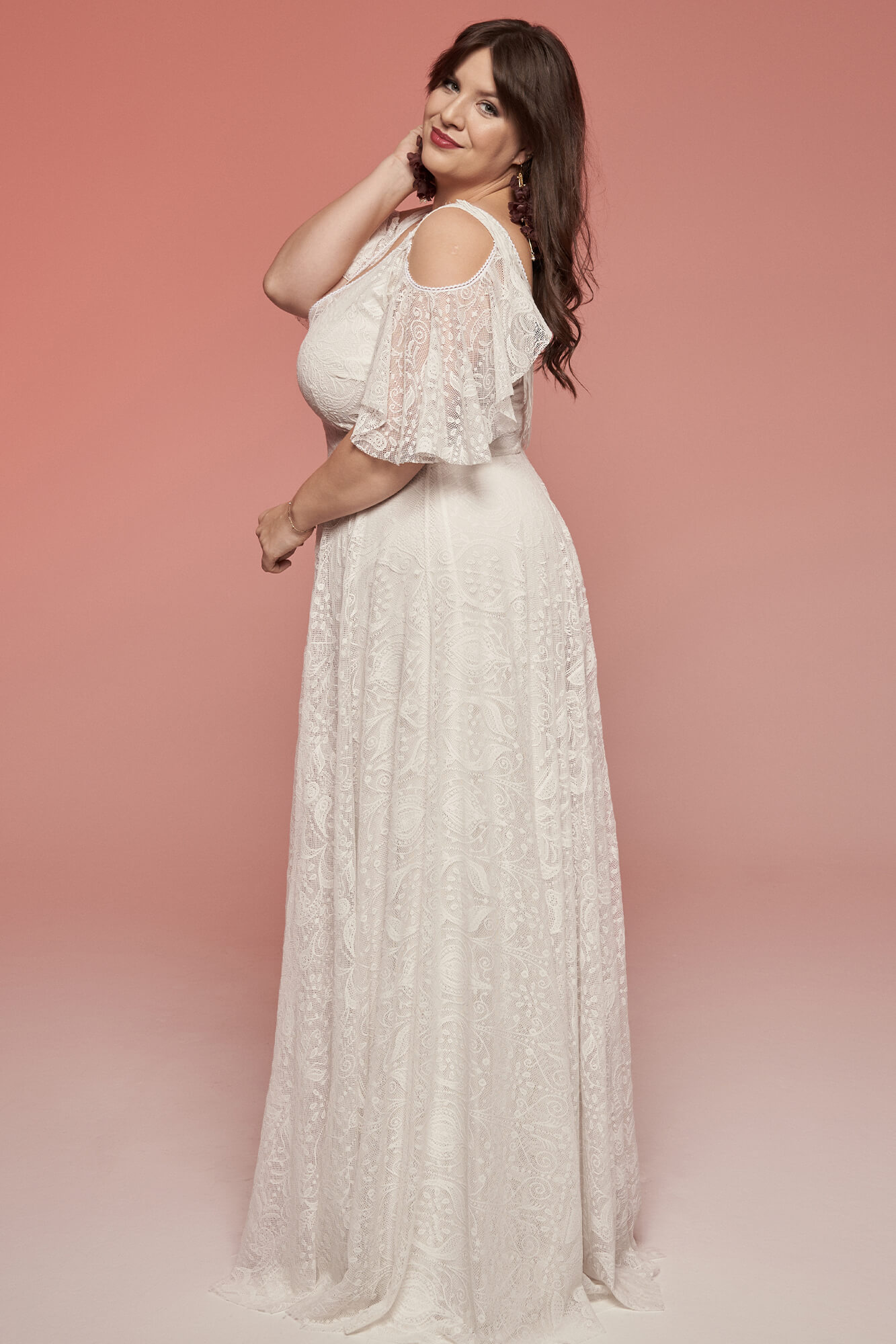 suknia ślubna z odkrytymi ramionami i koronkowym zdobieniem, w kolorze białym.